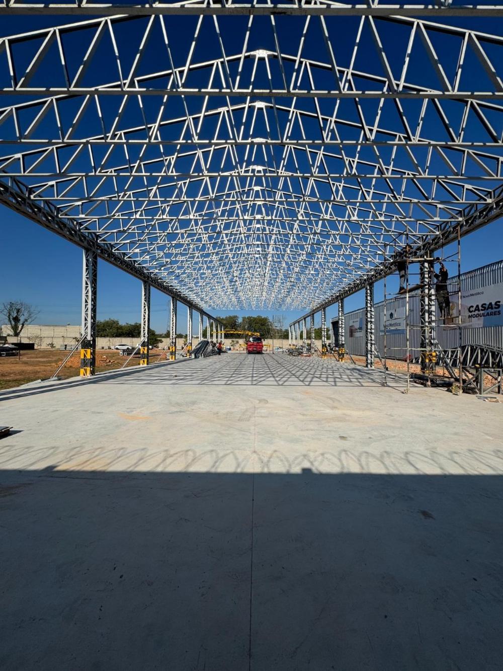 Galpão industrial em estrutura metálica da Nova Metálica, com equipe montando o fechamento lateral