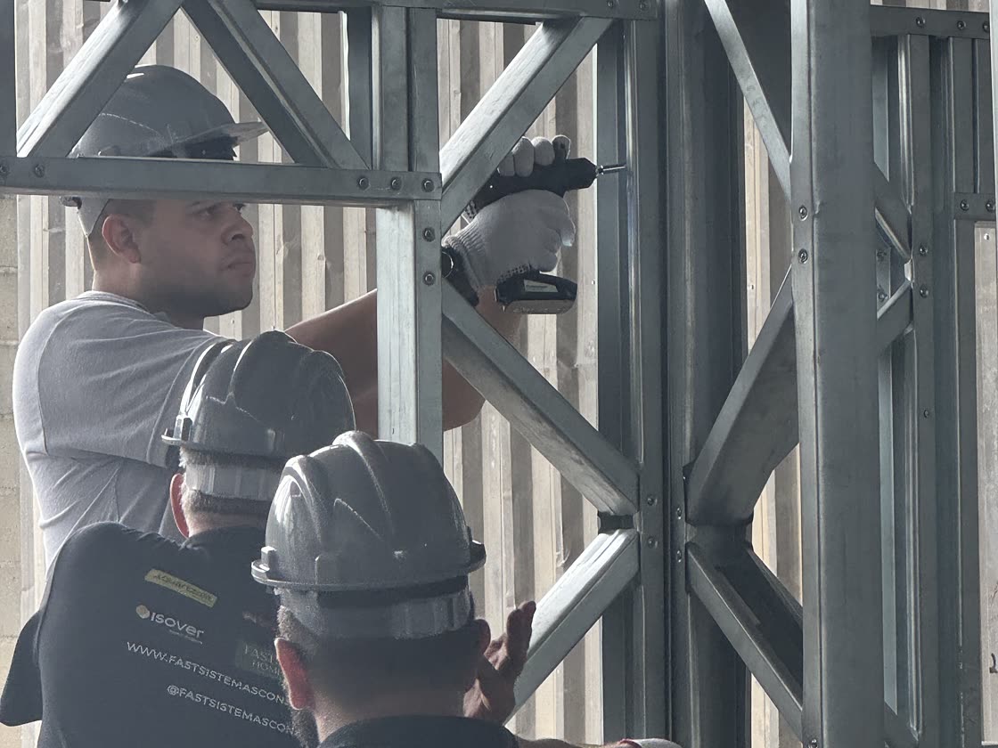 Participantes da imersão presencial parafusando um painel de parede em Light Steel Frame na fábrica